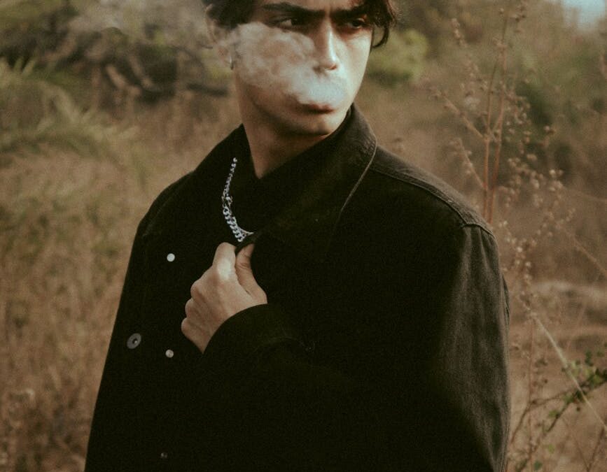 pensive male smoking cigarette in nature